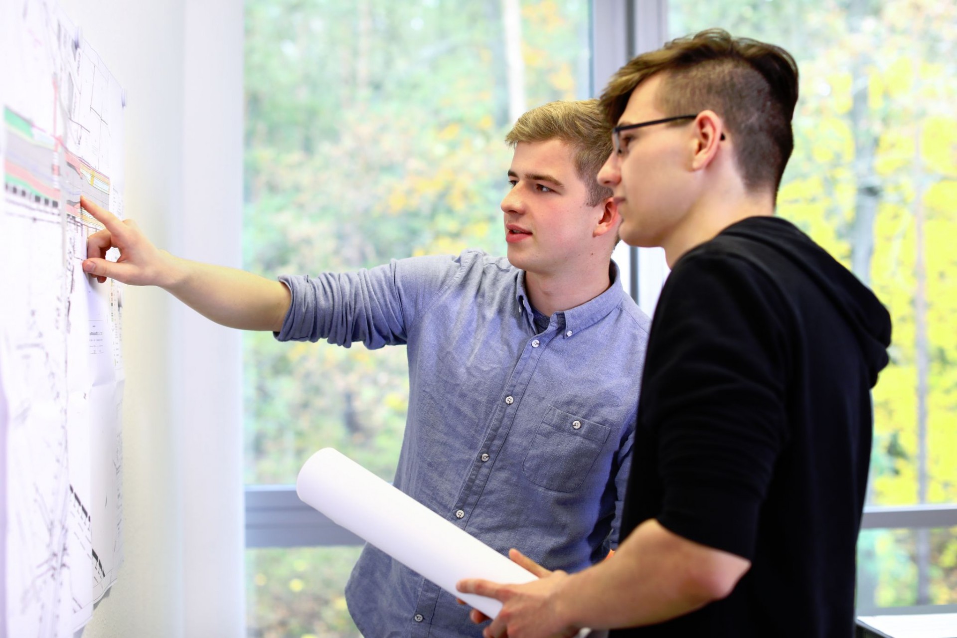 Zwei dual Studierende vor einer Stra&szlig;enkarte